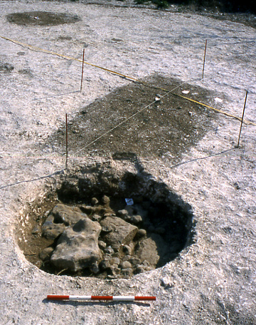 The rectangular central grave and circular pit filled with flint, plus the second grave in the background